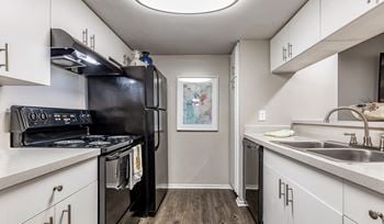 An apartment kitchen with black appliances and white cabinets